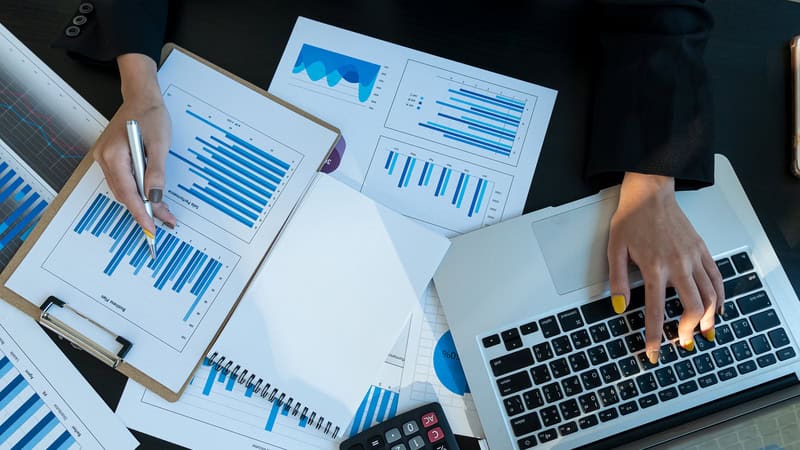 Marketing analyst reviewing advertising performance data with charts and laptop