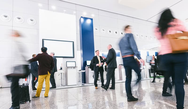 Crowd of business people at a trade show booth.