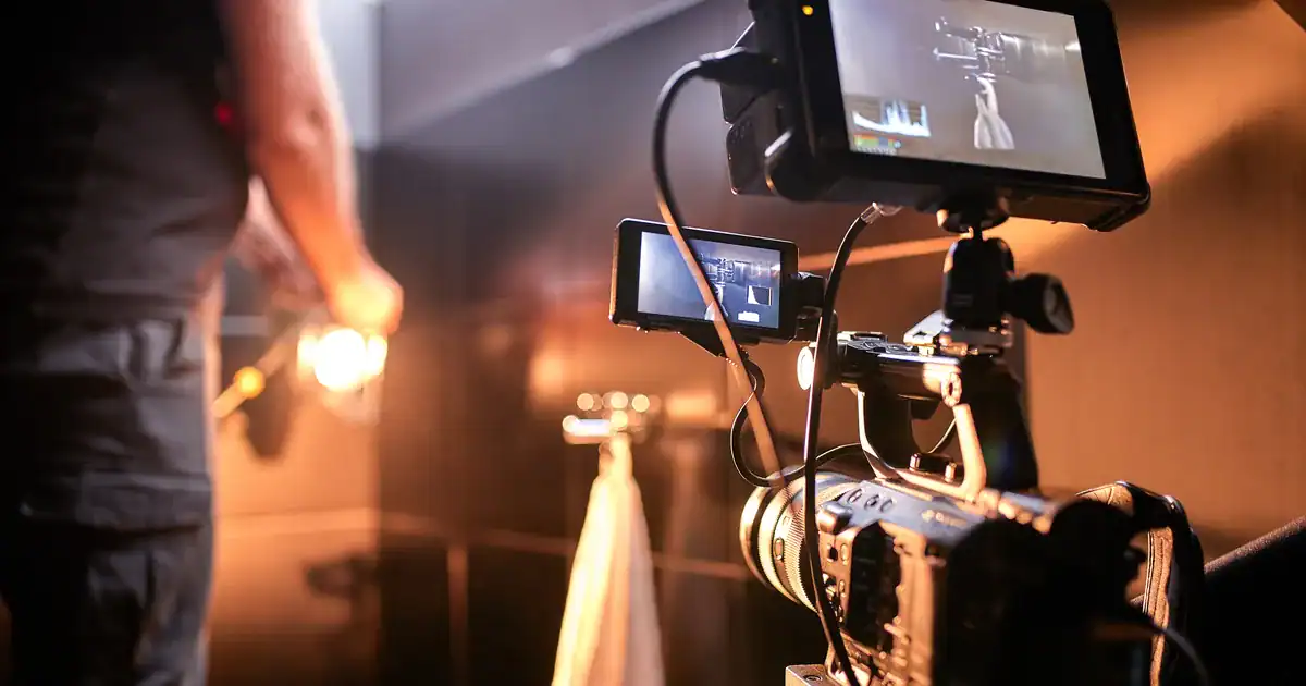 Video crew filming a commercial on set, with a cinema camera on a rig and two monitors showing the shot